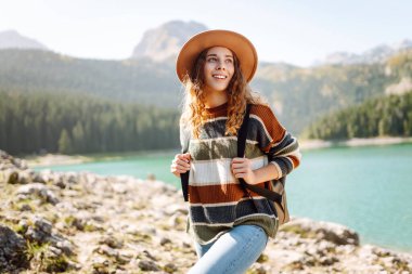 Tepede oturan ve doğanın tadını çıkaran genç bir kadın. Aktif hayat. Yaşam tarzı, seyahat, turizm