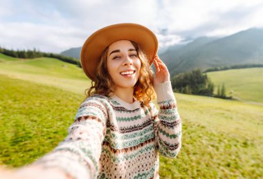 Doğada selfie çeken güzel bir genç kadın. Bloglama, iletişim, seyahat, turizm, doğa, aktif yaşam.