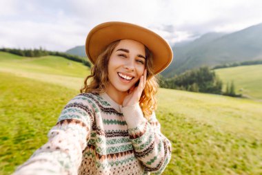 Doğada selfie çeken güzel bir genç kadın. Bloglama, iletişim, seyahat, turizm, doğa, aktif yaşam.