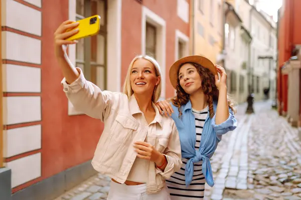 Two Beautiful Young Woman Friends Walking Together City Using Smartphone Imagens Royalty-Free