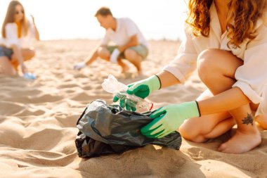Sahilde çöp. Leşçilik. Bir gönüllü okyanus kıyısında plastik şişe topluyor. Çevre koruma kavramı.