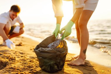 Sahilde çöp. Leşçilik. Bir gönüllü okyanus kıyısında plastik şişe topluyor. Çevre koruma kavramı.