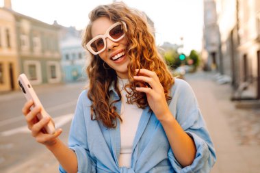 Sokakta cep telefonu kullanan güzel bir kadın. Gençlik konsepti. İş, teknoloji, blog, iletişim kavramı.