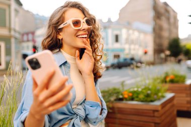 Sokakta cep telefonu kullanan güzel bir kadın. Gençlik konsepti. İş, teknoloji, blog, iletişim kavramı.
