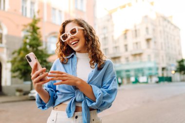 Sokakta cep telefonu kullanan güzel bir kadın. Gençlik konsepti. İş, teknoloji, blog, iletişim kavramı.