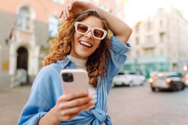 Sokakta cep telefonu kullanan güzel bir kadın. Gençlik konsepti. İş, teknoloji, blog, iletişim kavramı.