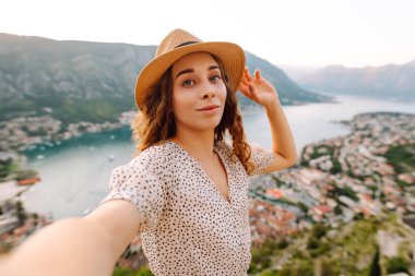 Cep telefonlu mutlu bir turist, selfie çekiyor, çekimlerin arka planında video bağlantısı ile iletişim kuruyor. Yaşam tarzı, seyahat, dinlenme, hafta sonu, aktif yaşam.