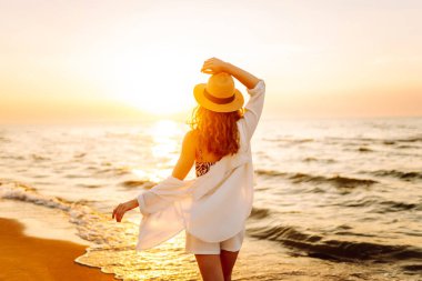 Yazın gün batımında sahilde dinlenen güzel kadının portresi. Seyahat, hafta sonu, rahatlama ve yaşam tarzı konsepti.