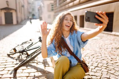 Yaz günü parkta bisikletli genç bir kadın cep telefonu kullanıyor. Selfie zamanı. Seyahat, hafta sonu, rahatlama ve yaşam tarzı konsepti.