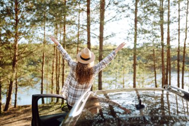 Genç bir kadın araba camından dışarı sarkmış tatillerinde eğleniyor ve eğleniyor. Yaz gezisi.