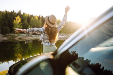 Genç bir kadın araba camından dışarı sarkmış tatillerinde eğleniyor ve eğleniyor. Yaz gezisi.