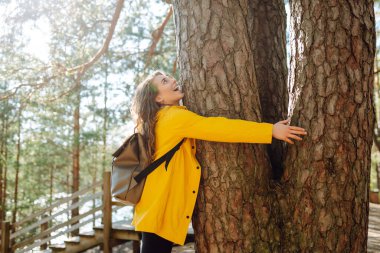Sırt çantalı bir kadın sonbahar ormanında yürüyüş yapıyor. Ormanda yaya olarak yürüyen bir yürüyüşçü. Gezgin doğanın tadını çıkarıyor. Hafta sonu, turizm.