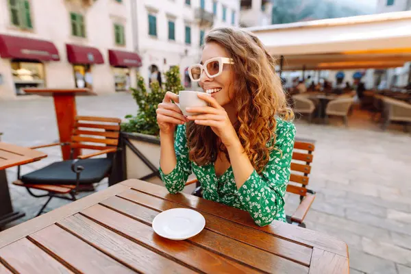 Die Frau Straßencafé Sitzt Mit Einer Tasse Kaffee Tisch Und lizenzfreie Stockbilder
