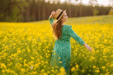 Güzel bir kadın sarı tarla kolza doğru koşar. Doğa, moda, yaz yaşam tarzı.