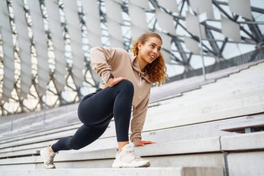 Gülen kadın sabah koşuya çıkmadan önce bacaklarını esnetiyor. Spor, spor ve sağlıklı vücut konsepti..