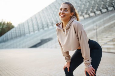 Gülen kadın sabah koşuya çıkmadan önce bacaklarını esnetiyor. Spor, spor ve sağlıklı vücut konsepti..