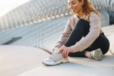 Gülen kadın sabah koşuya çıkmadan önce bacaklarını esnetiyor. Spor, spor ve sağlıklı vücut konsepti..
