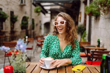 Genç bayan turist yaz gezisinde eski kasabada kahve içer. İnsanlar, moda, yaşam tarzı, seyahat ve tatiller