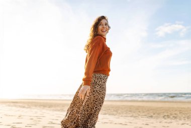 Günbatımında seyahat tatili sırasında dingin okyanus doğasının tadını çıkaran genç bir kadın. Seyahat, hafta sonu, rahatlama ve yaşam tarzı konsepti. 