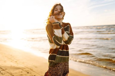 Günbatımında seyahat tatili sırasında dingin okyanus doğasının tadını çıkaran genç bir kadın. Seyahat, hafta sonu, rahatlama ve yaşam tarzı konsepti. 