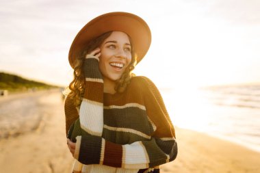 Günbatımında seyahat tatili sırasında dingin okyanus doğasının tadını çıkaran genç bir kadın. Seyahat, hafta sonu, rahatlama ve yaşam tarzı konsepti. 