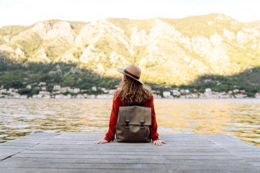 Sırt çantalı genç bir kadın göl kıyısında duruyor. İnanılmaz bir manzara. Doğanın tadını çıkarıyorum. Yaşam tarzı, seyahat, turizm konsepti.