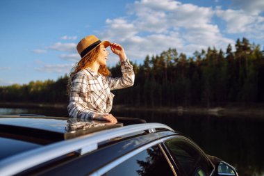 Genç bir kadın araba camından dışarı sarkmış tatillerinde eğleniyor ve eğleniyor. Yolculuk.