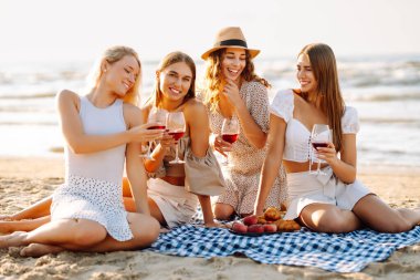 Şarap kadehleriyle poz veren mutlu genç kadınlar sahilde eğleniyor, sahilde bekarlığa veda partisini kutluyor ve tatillerinin tadını çıkarıyorlar..