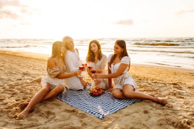 Şarap kadehleriyle poz veren mutlu genç kadınlar sahilde eğleniyor, sahilde bekarlığa veda partisini kutluyor ve tatillerinin tadını çıkarıyorlar..