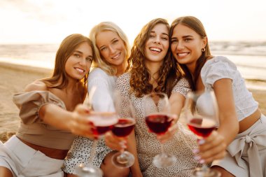 Şarap kadehleriyle poz veren mutlu genç kadınlar sahilde eğleniyor, sahilde bekarlığa veda partisini kutluyor ve tatillerinin tadını çıkarıyorlar..