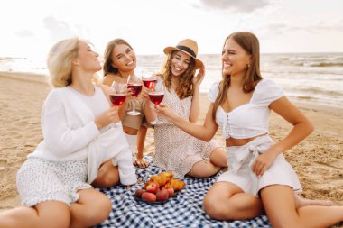 Şarap kadehleriyle poz veren mutlu genç kadınlar sahilde eğleniyor, sahilde bekarlığa veda partisini kutluyor ve tatillerinin tadını çıkarıyorlar..