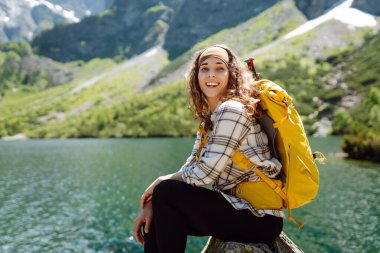 Gezgin kadın, dağ gölüne bak. Çekici kız açık hava yaşam tarzını seviyor. Doğası güzel görünüyor. Seyahat ve aktif yaşam konsepti. Macera ve dağlarda seyahat.