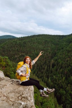 Yüksek kayalıkların zirvesindeki turist kadın. Spor ve aktif yaşam konsepti. Aktif kadın görkemli dağların güzel manzarasını seviyor. Seyahat, macera.