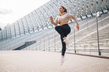 Sokakta koşmadan önce spor kıyafetleri giyen genç bir kadın ısınıyor. İnsanlar, spor, spor ve esneklik kavramı