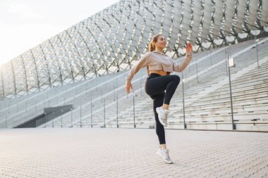 Sokakta koşmadan önce spor kıyafetleri giyen genç bir kadın ısınıyor. İnsanlar, spor, spor ve esneklik kavramı