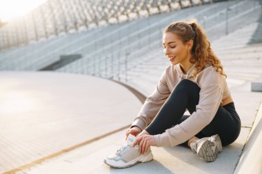Sokakta koşmadan önce spor kıyafetleri giyen genç bir kadın ısınıyor. İnsanlar, spor, spor ve esneklik kavramı