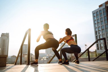 Dışarıda egzersiz yapan iki çekici kadın. Esneme, zindelik, spor ve sağlıklı yaşam tarzı kavramı