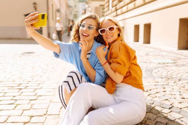 Arkadaş canlısı bir özçekim. Yakışıklı genç kızlar sokakta yürürken selfie çekiyorlar. Moda, seyahat, teknoloji, blog konsepti.