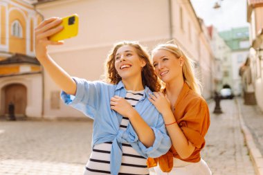 Arkadaş canlısı bir özçekim. Yakışıklı genç kızlar sokakta yürürken selfie çekiyorlar. Moda, seyahat, teknoloji, blog konsepti.