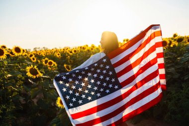 Ayçiçeği tarlasında Amerikan bayrağı taşıyan güzel bir kadın. Özgürlük günü. Bağımsızlık Günü. 4 Temmuz.