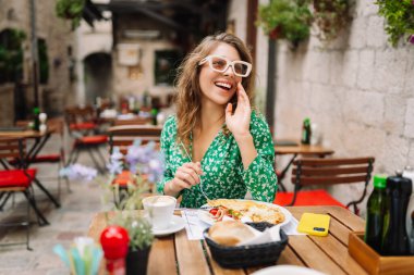 İtalyan makarnası yiyen ve Roma caddesindeki restoranda kahve içen bir kadın. İtalyan gastronomisi ve seyahat kavramı. Turizm, yiyecek ve içecek.