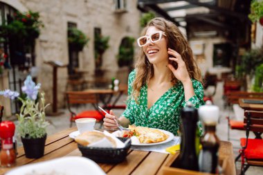 İtalyan makarnası yiyen ve Roma caddesindeki restoranda kahve içen bir kadın. İtalyan gastronomisi ve seyahat kavramı. Turizm, yiyecek ve içecek.