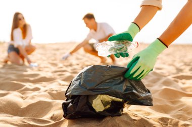Sahilde çöp. Gönüllü eylemciler sahil bölgesindeki çöpleri topluyor. Okyanus kıyısında çöp torbası içinde kadın erkekler. Dünya günü.