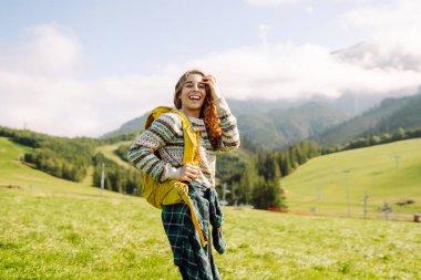 Kadın turist, yaz güneşli bir günde, güneş ışığı altında dağın zirvesinde yürüyor. Seyahat, doğa konsepti..