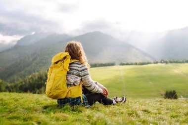 Kadın turist, yaz güneşli bir günde, güneş ışığı altında dağın zirvesinde yürüyor. Seyahat, doğa konsepti..
