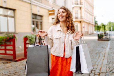 Alışveriş merkezinden alışverişlerle çıkan genç ve güzel bir kadın. Tüketim, moda, alışverişler, alışveriş, yaşam tarzı konsepti.