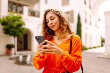 Avrupa 'nın yaz caddesinde akıllı telefon kullanan güzel bir kadın. Blogculuk, teknoloji, yaşam tarzı, seyahat, turizm, aktif yaşam.