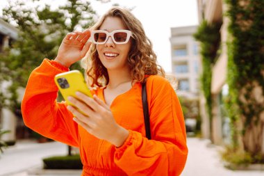 Avrupa 'nın yaz caddesinde akıllı telefon kullanan güzel bir kadın. Blogculuk, teknoloji, yaşam tarzı, seyahat, turizm, aktif yaşam.