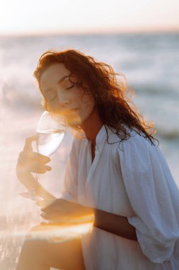 Genç ve tasasız bir kadın gün batımında sahilde yürüyor, dans ediyor ve gülümsüyor. Yaz zamanı. Seyahat, hafta sonu, rahatlama ve yaşam tarzı konsepti.