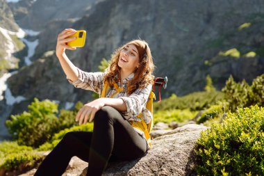 Olumlu turist kadın dışarıda fotoğraf çekiyor, vadi dağları manzaralı selfie çekiyor, seyahat maceralarını paylaşıyor. Yaşam tarzı, seyahat, turizm, aktif yaşam.